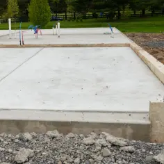 Nowa płyta fundamentowa z wystającymi rurami hydraulicznymi, gotowa na budowę domu.