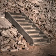 Betonowe schody pośrodku sterty gruzu budowlanego.