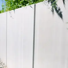 Nowoczesny, tani murek oporowy z betonu, otoczony żwirem i zielenią.