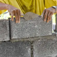 Budowniczy układa bloczki betonowe fundamentowe, tworząc solidną podstawę.