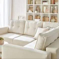 Przytulny salon w odcieniach bieli. Jasna sofa, białe meble i dekoracje tworzą spokojną atmosferę.