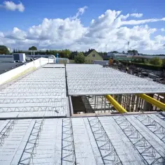 Budowa stropu typu Rector. Metalowe kratownice i beton tworzą solidną konstrukcję.